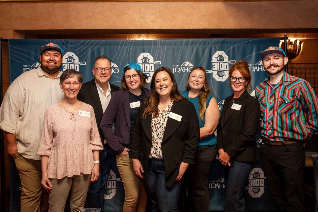 Landing Page The Visit Idaho team stands smiling in front of a backdrop with The 3100™ and Visit Idaho logos at the Egyptian Theatre.